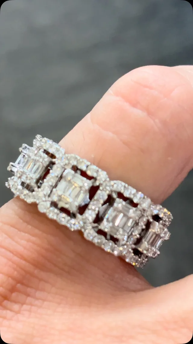 An emerald-cut diamond halo band worn on a finger.