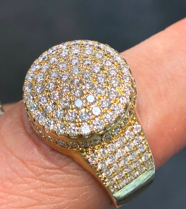 A yellow-gold pavé diamond dome ring photographed on a finger.