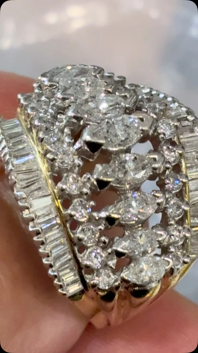 A close-up of a sculptural ring set with oval and baguette diamonds.